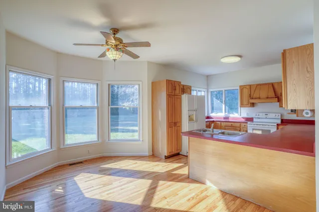 a view of a kitchen with kitchen island a counter top space appliances and a ceiling fan