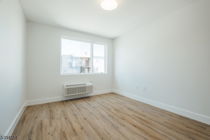 67 Summer Avenue, Unit 202 Newark, NJ 07104 - Photo 13 of 26 an empty room with wooden floor and windows