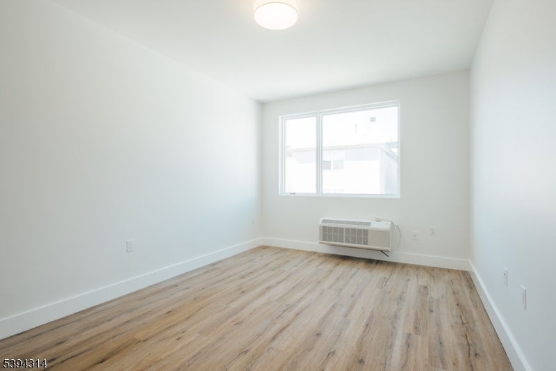 67 Summer Avenue, Unit 202 Newark, NJ 07104 - Photo 22 of 26 an empty room with wooden floor and windows