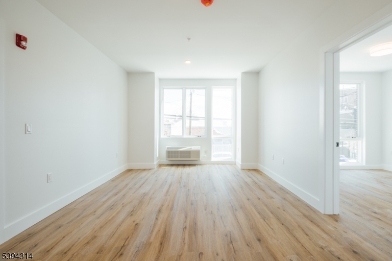 67 Summer Avenue, Unit 202 Newark, NJ 07104 - Photo 5 of 26 a view of an empty room with wooden floor and a window