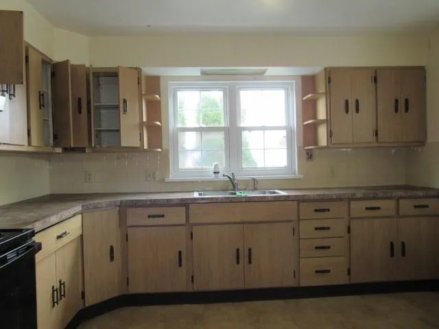 a kitchen with stainless steel appliances granite countertop white cabinets sink and window