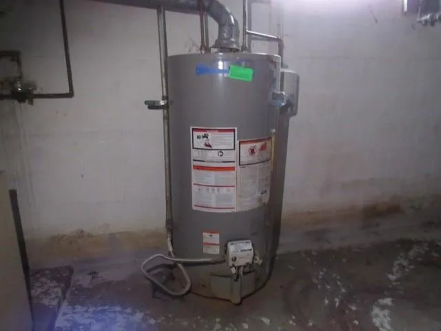 a room with water heater and wooden cabinets