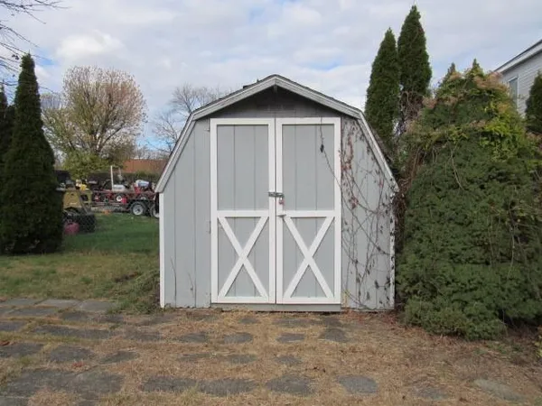 a view of wooden house with a yard and a large tree