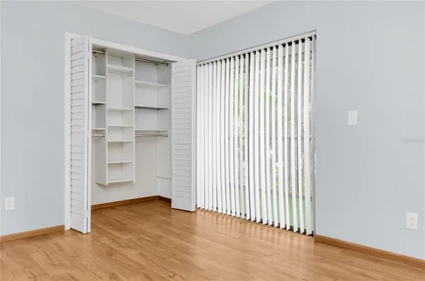 an empty room with wooden floor closet and windows