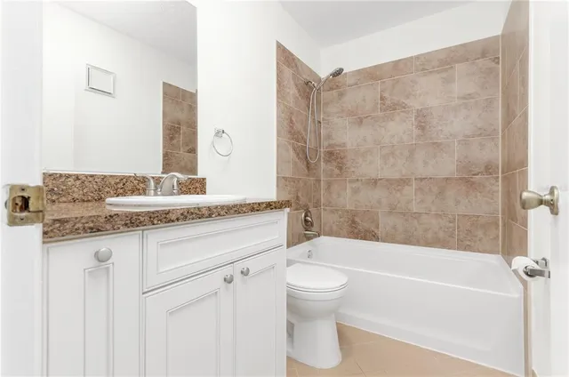 a bathroom with a granite countertop bathtub shower sink vanity mirror and toilet