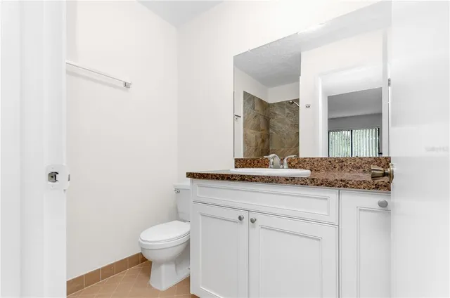 a bathroom with a granite countertop toilet a sink and a mirror