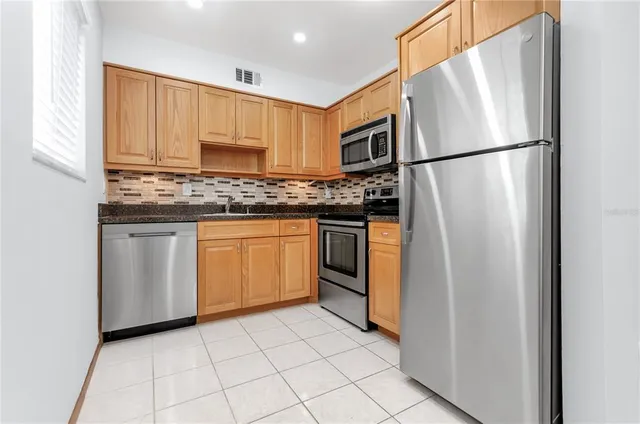 a kitchen with stainless steel appliances granite countertop a refrigerator sink and stove