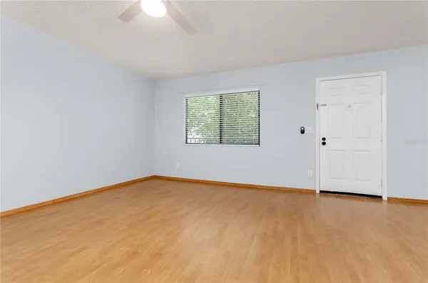 an empty room with wooden floor chandelier fan and windows