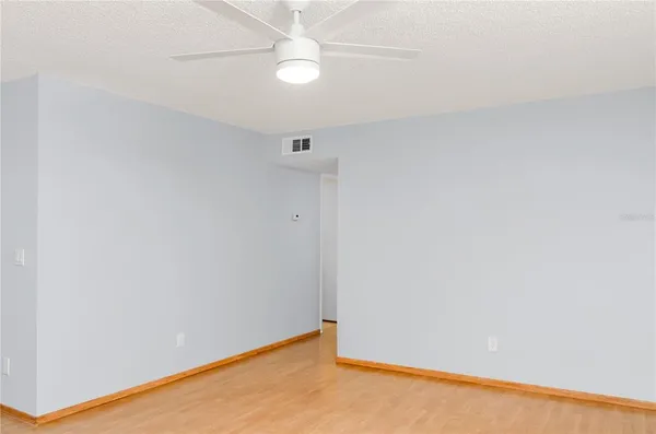 an empty room with a ceiling fan and wooden floor