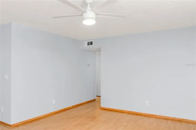 an empty room with a ceiling fan and wooden floor