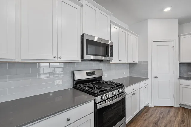 a kitchen with granite countertop white cabinets and stainless steel appliances