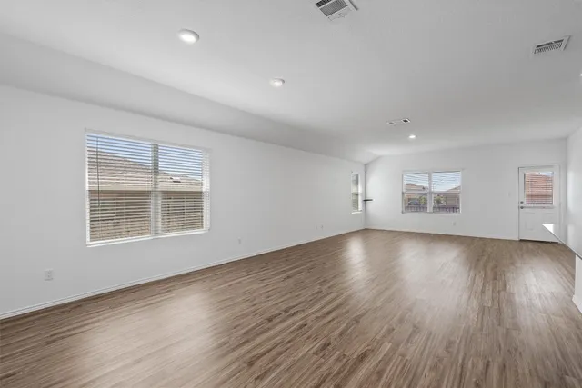 an empty room with wooden floor and windows