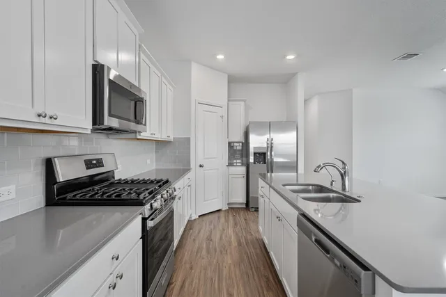 a kitchen with kitchen island stainless steel appliances a sink stove and refrigerator