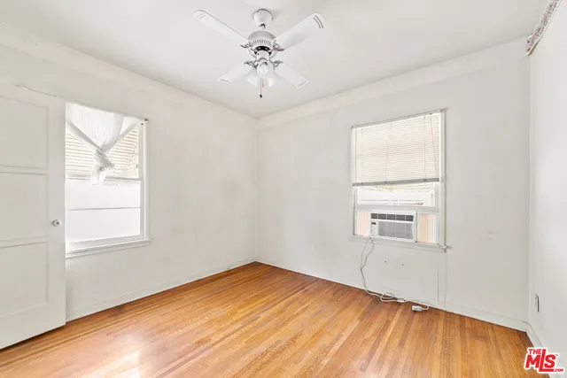 a view of empty room with wooden floor and fan