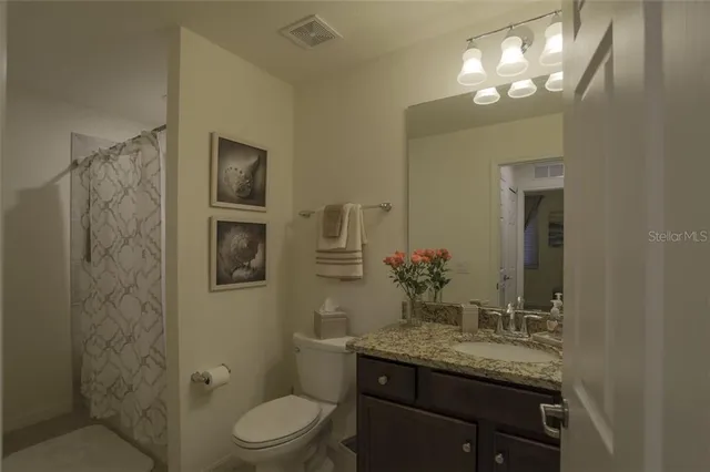 a bathroom with a granite countertop sink toilet a mirror and a shower