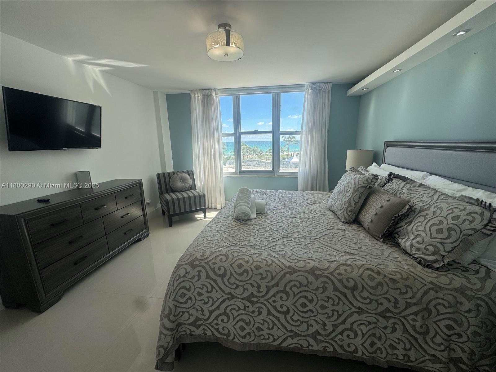 5161 Collins Avenue, Unit 514 Miami Beach, FL 33140 - Photo 13 of 34 a bedroom with a large bed and a flat screen tv