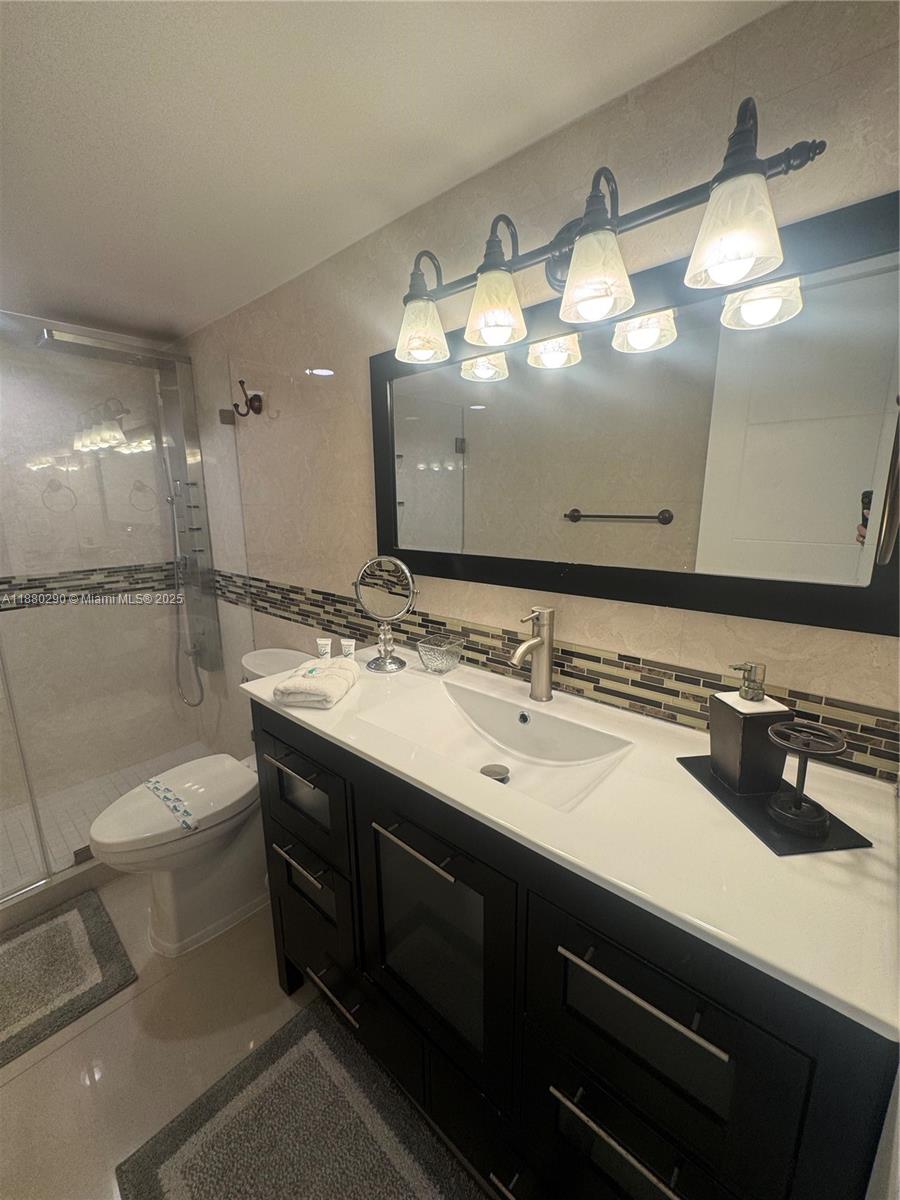 5161 Collins Avenue, Unit 514 Miami Beach, FL 33140 - Photo 20 of 34 a bathroom with a sink a toilet and a mirror