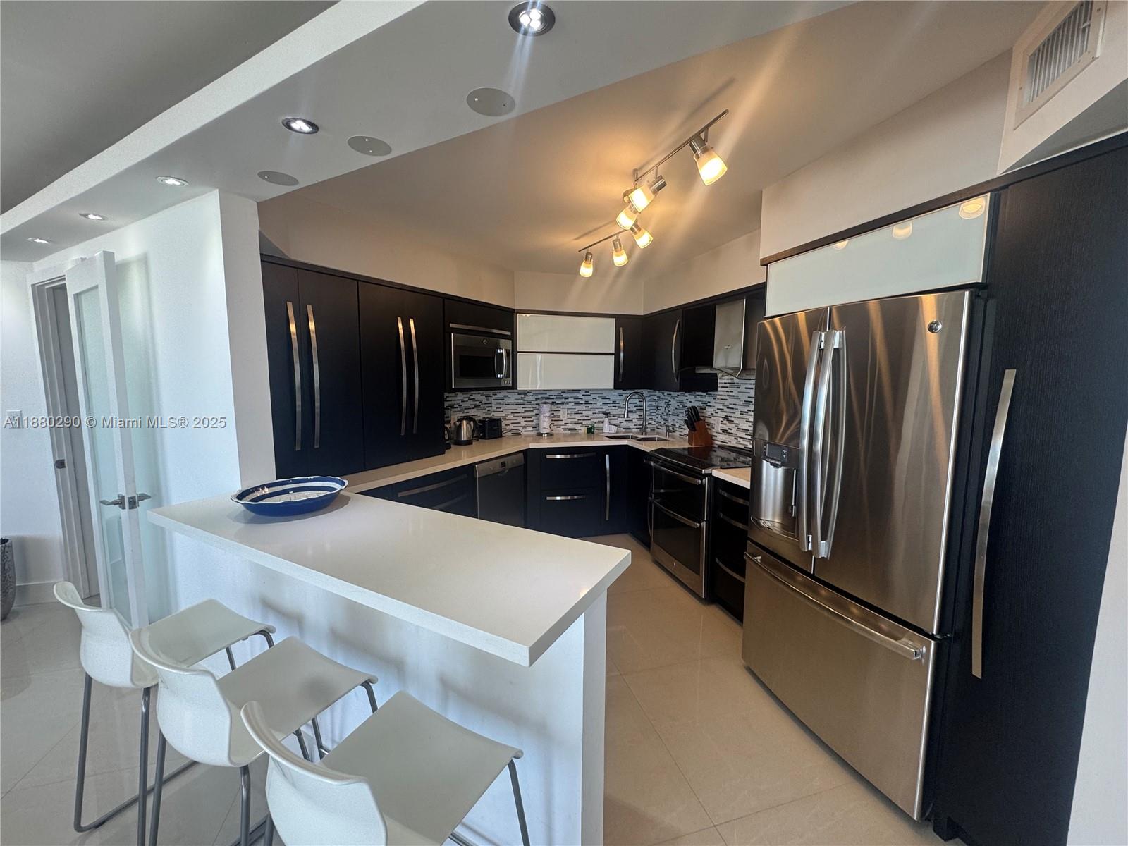 5161 Collins Avenue, Unit 514 Miami Beach, FL 33140 - Photo 8 of 34 a kitchen with refrigerator and chairs