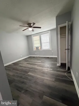en empty room with windows and ceiling fan
