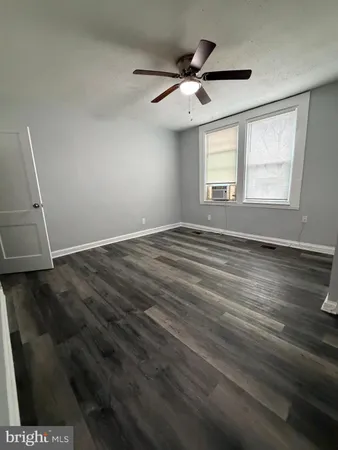 an empty room with wooden floor fan and windows