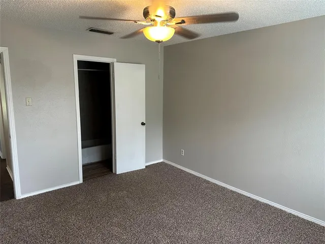 a view of an empty room with window and a ceiling fan