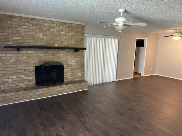 an empty room with wooden floor fireplace cabinet and windows