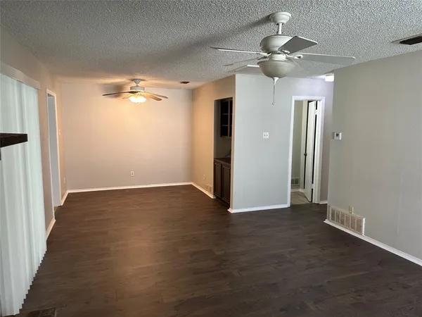 an empty room with wooden floor and a ceiling fan