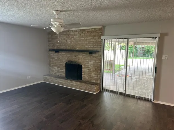 an empty room with wooden floor fireplace and windows