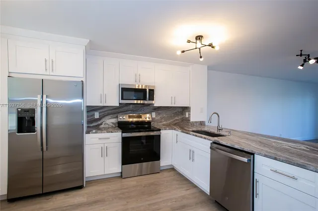 a kitchen with a sink stainless steel appliances and white cabinets