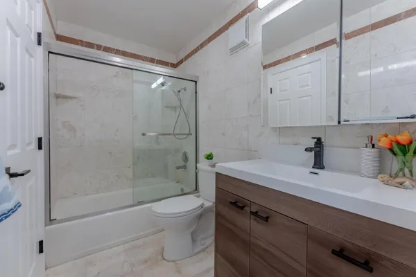 a bathroom with a shower sink vanity mirror and toilet