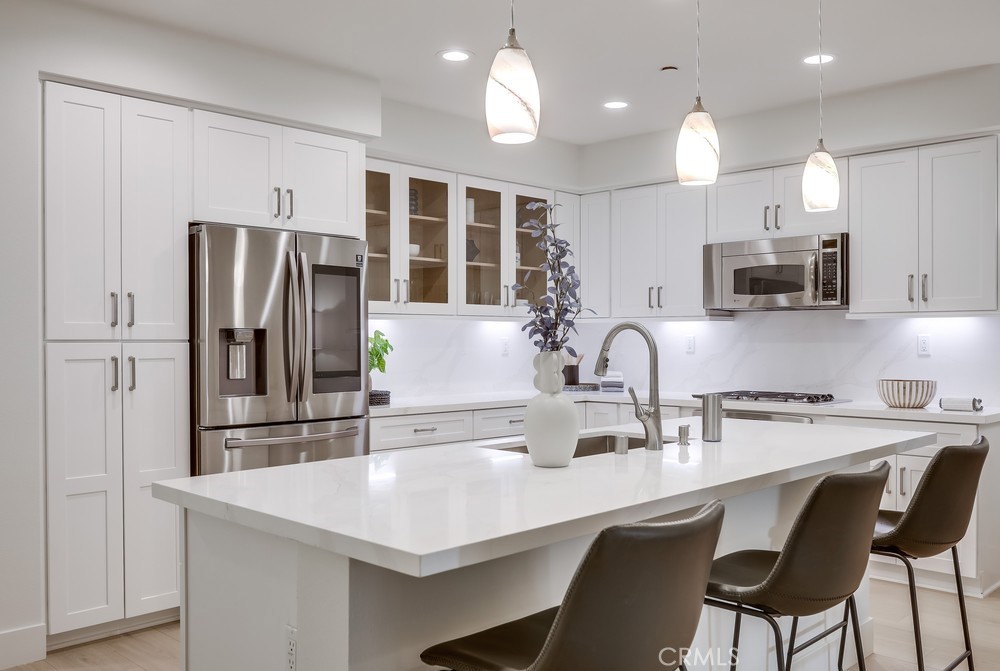 617 Rockefeller Irvine, CA 92612 - Photo 1 of 1 a kitchen with stainless steel appliances granite countertop a dining table chairs refrigerator and microwave