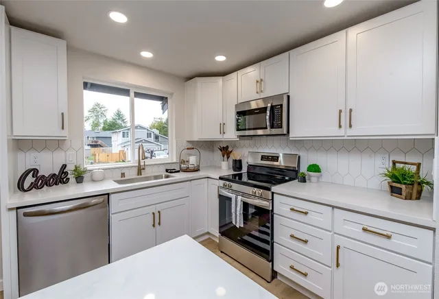 a kitchen with white cabinets appliances a sink and a window