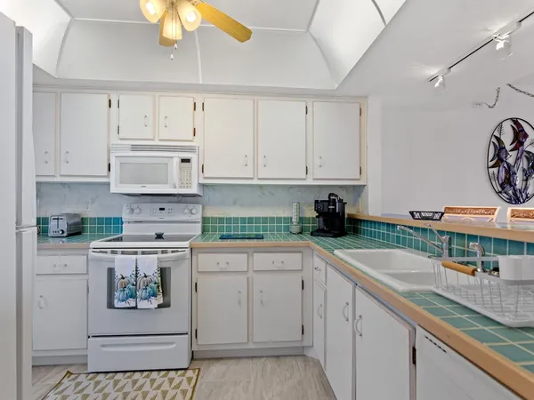 a kitchen with granite countertop white cabinets and white appliances