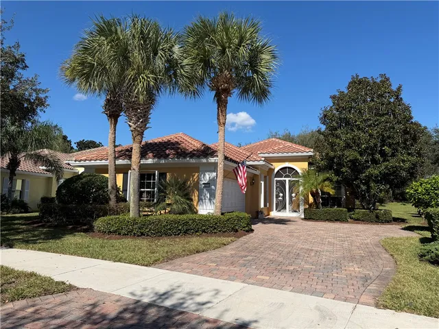 a front view of a house with garden and trees