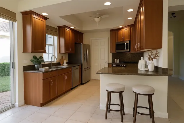 a kitchen with stainless steel appliances kitchen island granite countertop a sink and a refrigerator