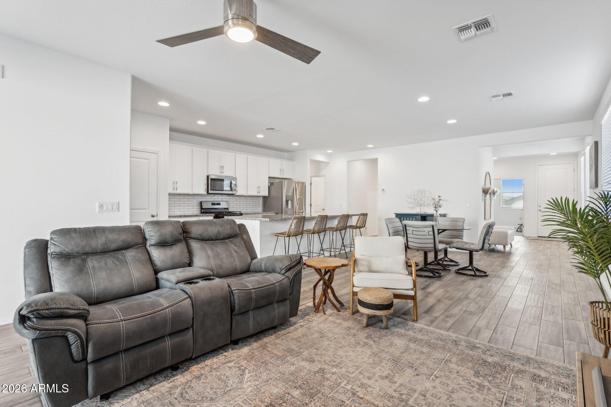 17334 West Wandering Creek Road Goodyear, AZ 85338 - Photo 16 of 67 a living room with furniture and a dining table with kitchen view