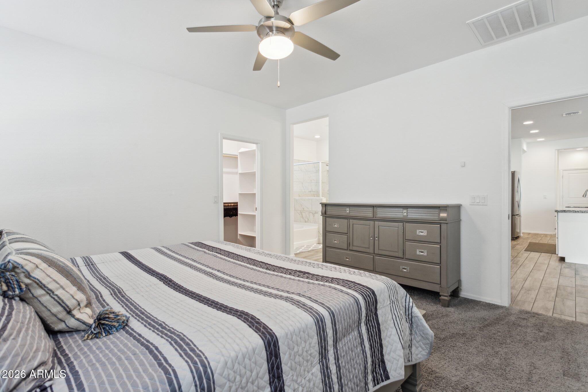 17334 West Wandering Creek Road Goodyear, AZ 85338 - Photo 18 of 67 a bedroom with a bed and a chandelier
