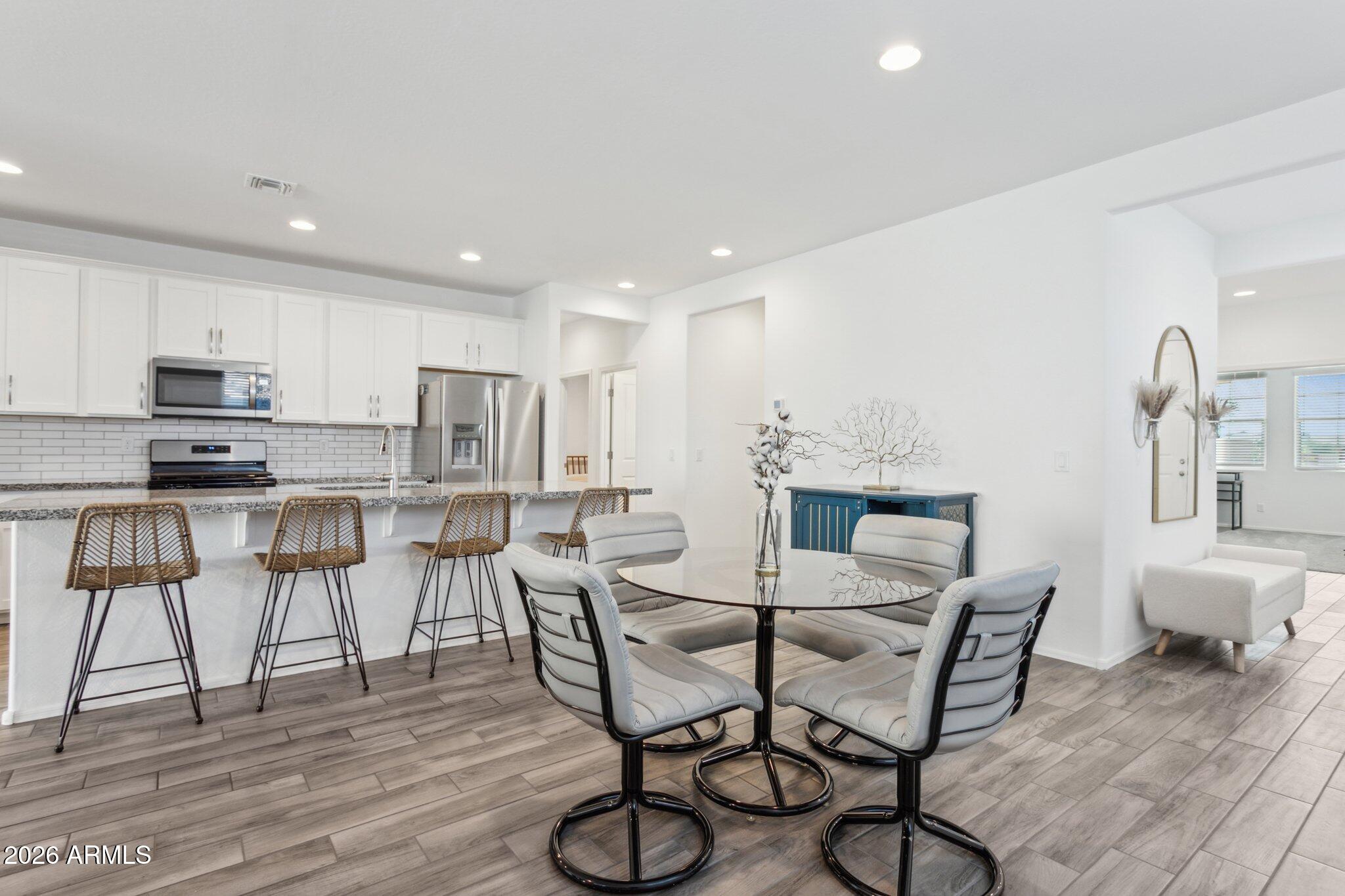 17334 West Wandering Creek Road Goodyear, AZ 85338 - Photo 9 of 67 a view of a dining room with furniture and wooden floor