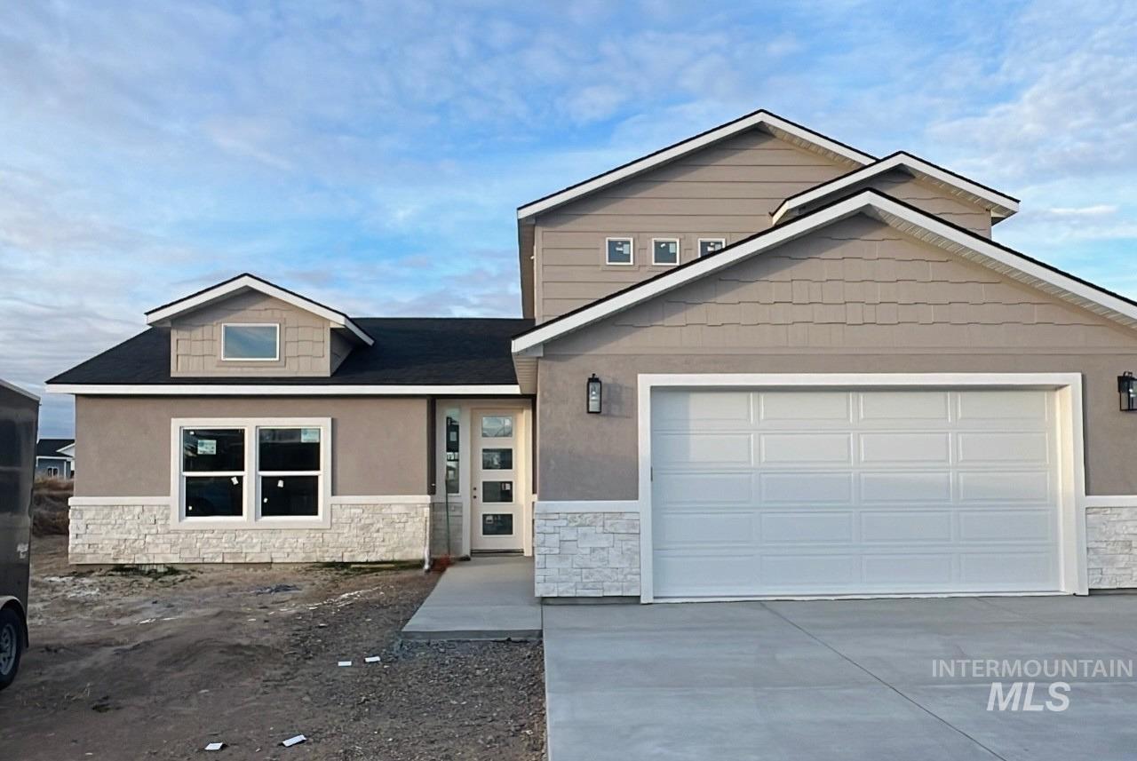 View of front of property with stone siding, driveway, roof with shingles, and an attached garage