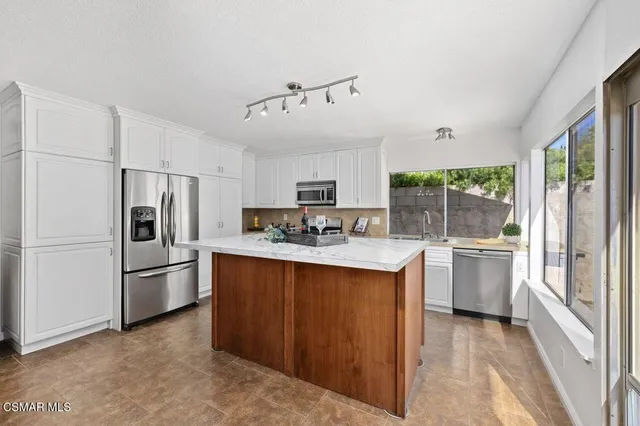 a kitchen with stainless steel appliances granite countertop a refrigerator and a stove top oven