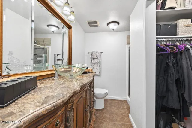 a bathroom with a granite countertop sink a large mirror and a toilet