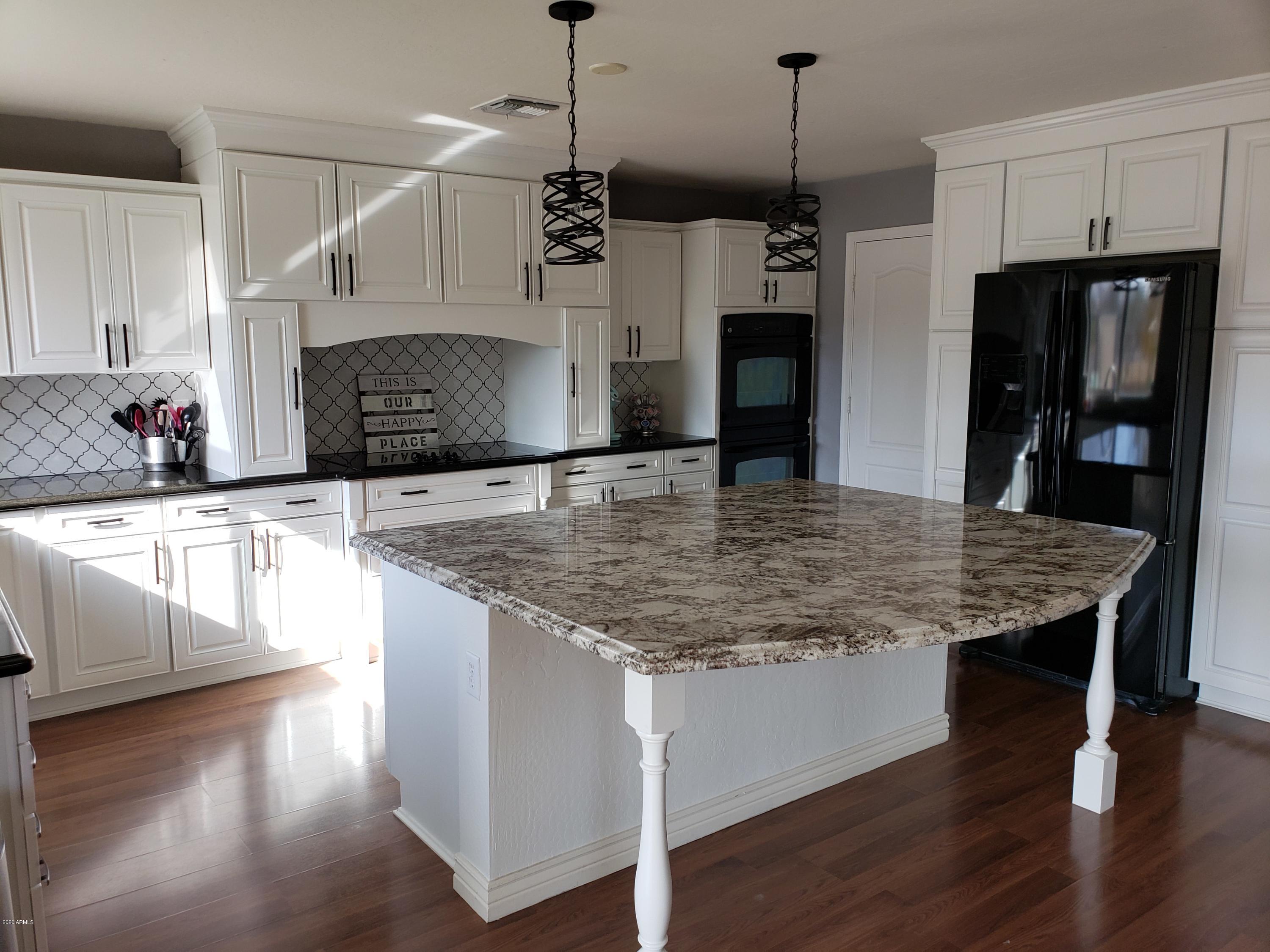 2917 West Fremont Rd. Phoenix, AZ 85041 - Photo 13 of 41 a kitchen with kitchen island granite countertop a stove a sink and a refrigerator