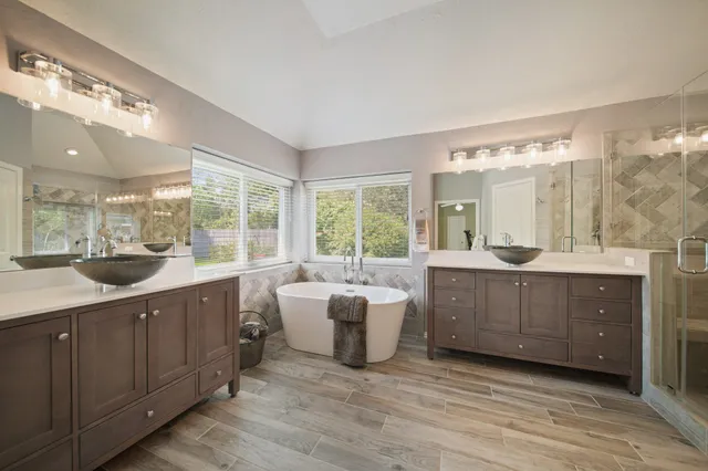 a large bathroom with a double vanity sink a large mirror and a bathtub