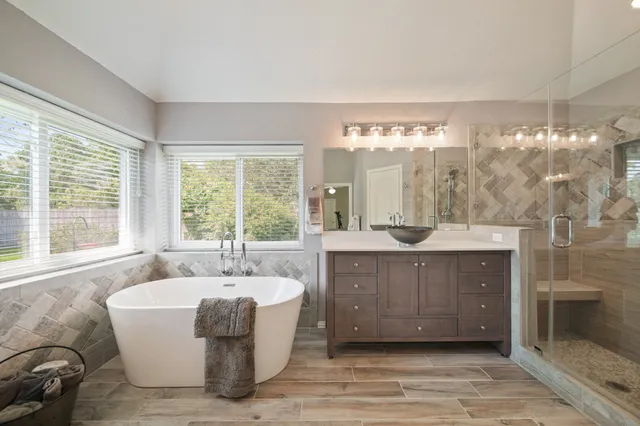 a spacious bathroom with a bathtub a sink and a large mirror