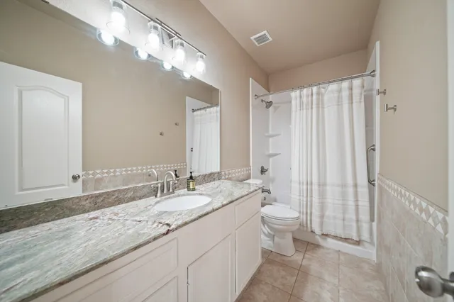 a bathroom with double vanity sinks a toilet a mirror and shower