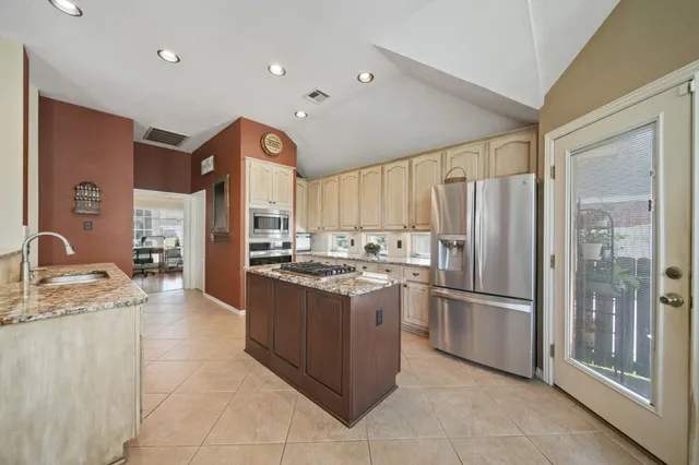 a kitchen with stainless steel appliances granite countertop a refrigerator and a stove top oven