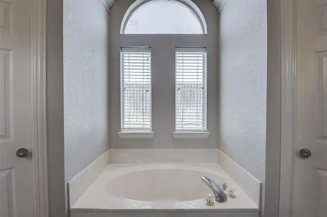 a white bath tub sitting in a bathroom next to a window