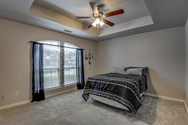 a bed sitting in a spacious bedroom next to a window