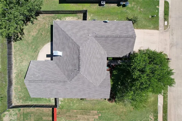 an aerial view of a house with a yard and large tree