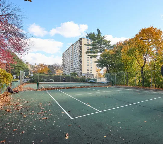 a view of a tennis ground with large trees